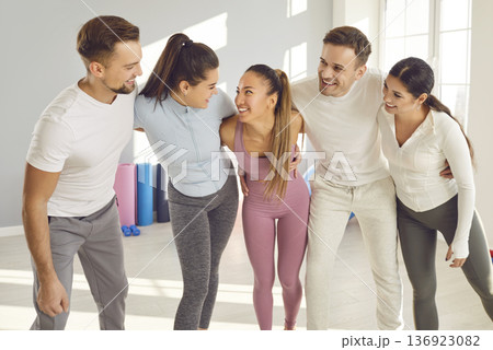 Portrait of happy joyful sporty people group standing in a row in gym after successful fit training Portrait of happy joyful sporty people group standing in a row in gym after successful fit training 136923082