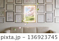 Above a beige sofa, a glowing picture frame reveals a spring meadow with cherry blossoms 136923745