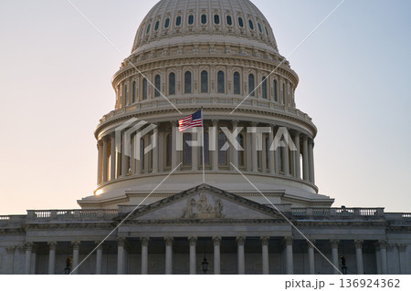 Last beams of golden sunlight on the United States Capitol Building in Washington, DC, with the American flag waving. Dramatic view 136924362