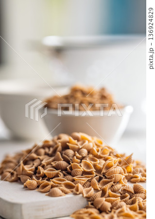 Wholegrain conchiglie pasta on white table. Wholegrain conchiglie pasta on white table. 136924829