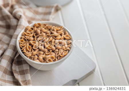 Wholegrain conchiglie pasta in bowl on white table. 136924831