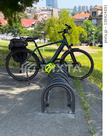 Bicycle parked outdoors with helmet on a stand. Urban mobility, active lifestyle and eco-friendly transport. Bicycle parked outdoors with helmet on a stand. Urban mobility, active lifestyle and eco-friendly transport. 136924891