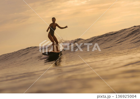 Serene Scene Of Woman Balancing On Her Surfboard During Sunset By Peaceful Ocean Serene Scene Of Woman Balancing On Her Surfboard During Sunset By Peaceful Ocean 136925004
