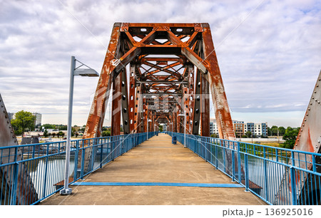Pedestrian walkway on the rusty steel truss Junction Bridge over the Arkansas River, with the USS Razorback submarine visible in Little Rock, Arkansas, United States. 136925016
