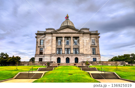 Arkansas State Capitol building in Little Rock. Historic Neoclassical government architecture features a limestone facade and dome under a blue sky with clouds 136925019