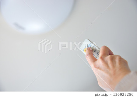 LED照明のリモコンを操作する手元 136925286
