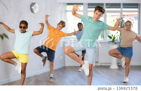 Girls and boys doing dance workout during group class in fitness center Girls and boys doing dance workout during group class in fitness center 136925378