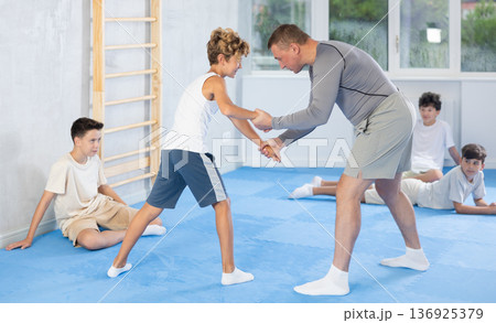 Judo teenager kids and trainer engaged in judo class in dojo at gym Judo teenager kids and trainer engaged in judo class in dojo at gym 136925379