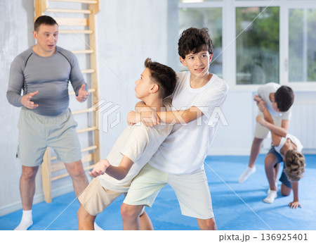 Teen boys trying to escape rear bear in training bout during self defense course Teen boys trying to escape rear bear in training bout during self defense course 136925401