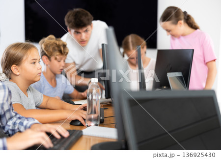Preteen girl working with computer programs in training room Preteen girl working with computer programs in training room 136925430