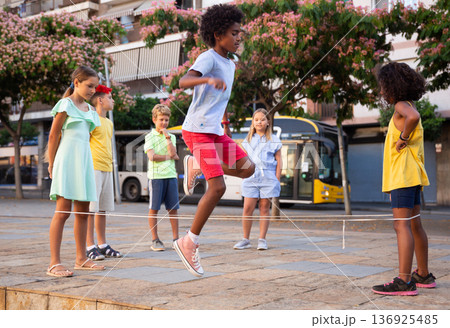 Happy preteen kids skipping on chinese jump rope 136925485