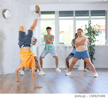 Preteen b-boy doing hands hops during training in dance class 136925486