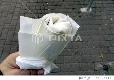 Enjoying a Doner Kebab While Walking on a City Street in the Afternoon Enjoying a Doner Kebab While Walking on a City Street in the Afternoon 136925531