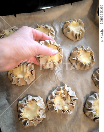 Laying out traditional Karelian rye flour kalitki with potatoes on a baking sheet. Laying out traditional Karelian rye flour kalitki with potatoes on a baking sheet. 136926169