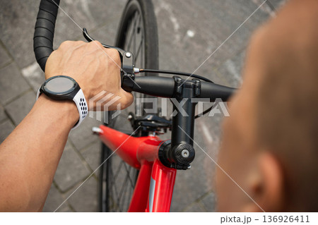 Close up of smartwatch on cyclist wrist on bicycle handlebar Close up of smartwatch on cyclist wrist on bicycle handlebar 136926411