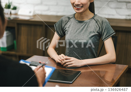 スポーツジムで手続きの説明を受ける女性 スポーツジムで手続きの説明を受ける女性 136926487