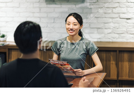 スポーツジムで手続きの説明を受ける女性 136926491