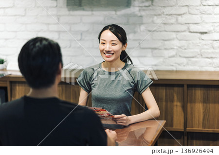 スポーツジムで手続きの説明を受ける女性 136926494