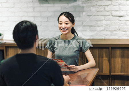 スポーツジムで手続きの説明を受ける女性 136926495