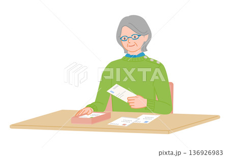 シニア女性がはがきを保管トレーに入れる整理シーン 136926983
