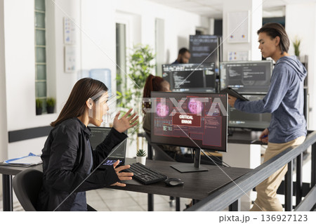 Asian female technology professional reacts to bad news on device screen, signaling computer crash, virus infection, or network error during office work in a high pressure IT environment. Asian female technology professional reacts to bad news on device screen, signaling computer crash, virus infection, or network error during office work in a high pressure IT environment. 136927123