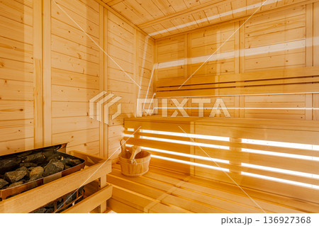Interior of a traditional wood sauna room featuring a bucket and heated stones Interior of a traditional wood sauna room featuring a bucket and heated stones 136927368