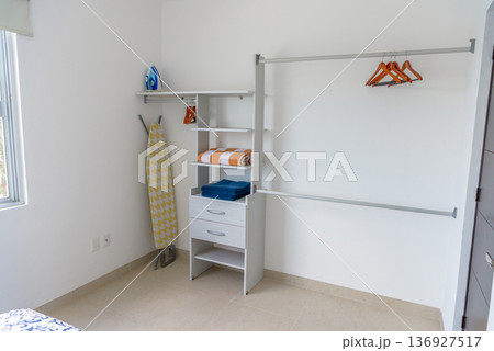 Bedroom closet with ironing board and organized storage shelves Bedroom closet with ironing board and organized storage shelves 136927517
