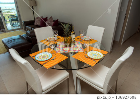 Round glass dining table set with colorful placemats 136927608