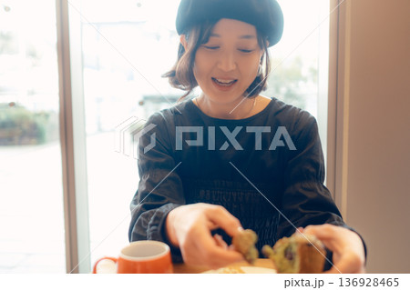 カフェでパンを食べる日本人女性 136928465