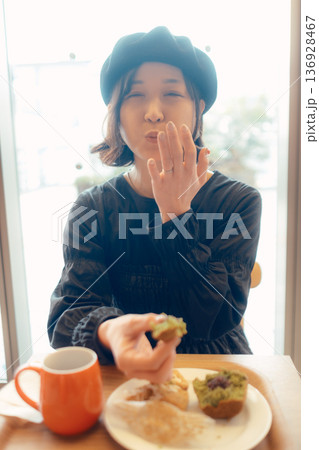 カフェでパンを食べる日本人女性 136928467