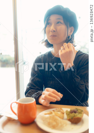 カフェでパンを食べる日本人女性 136928472