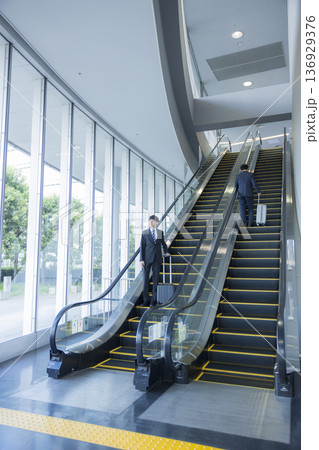 エスカレーターに乗るビジネスマン 136929376