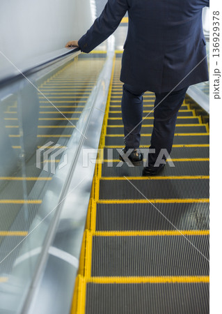 エスカレーターに乗るビジネスマン 136929378