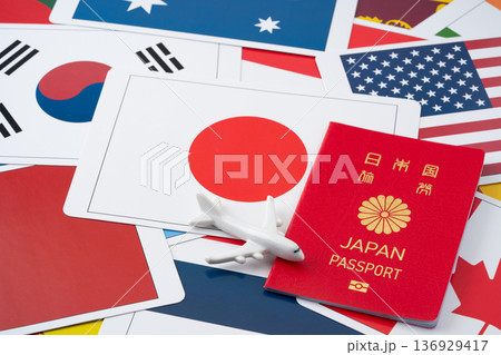 たくさんの国旗のカードを背景に赤い日本のパスポートと飛行機のミニチュア たくさんの国旗のカードを背景に赤い日本のパスポートと飛行機のミニチュア 136929417