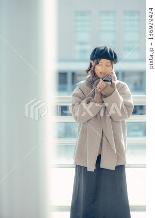冬の屋外で待ち合わせ中スマートフォンを確認する女性 136929424