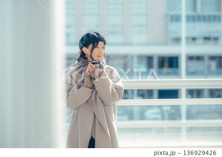 冬の屋外で待ち合わせ中スマートフォンを確認する女性 冬の屋外で待ち合わせ中スマートフォンを確認する女性 136929426