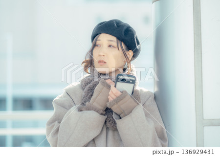 冬の屋外で待ち合わせ中スマートフォンを確認する女性 136929431