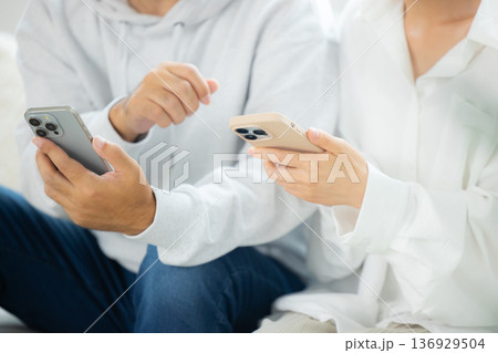 リビングでスマホを見るミドルの夫婦 リビングでスマホを見るミドルの夫婦 136929504