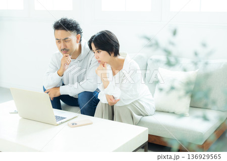 リビングでパソコンを見るミドル夫婦　 136929565