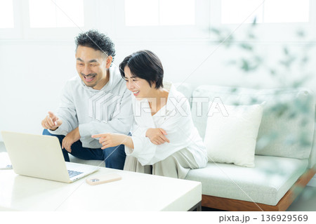 リビングでパソコンを見るミドル夫婦　 136929569