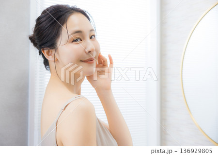 洗面所で鏡を見る若い女性　  136929805