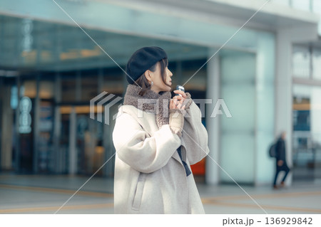 冬の屋外で待ち合わせ中スマートフォンを確認する女性 136929842