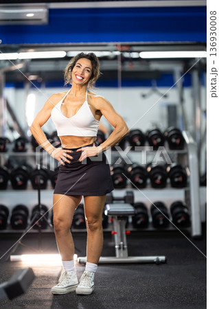 Fit woman smiling in gym showing health and confidence Fit woman smiling in gym showing health and confidence 136930008