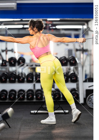 Woman exercising back muscles using cable machine in gym Woman exercising back muscles using cable machine in gym 136930051