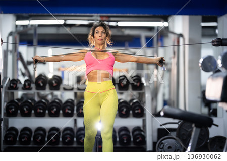 Woman training arms using cable crossover machine in gym Woman training arms using cable crossover machine in gym 136930062