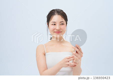 手鏡で肌の状態を確かめる若い女性 手鏡で肌の状態を確かめる若い女性 136930423