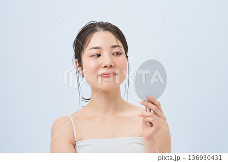 手鏡で肌の状態を確かめる若い女性 手鏡で肌の状態を確かめる若い女性 136930431