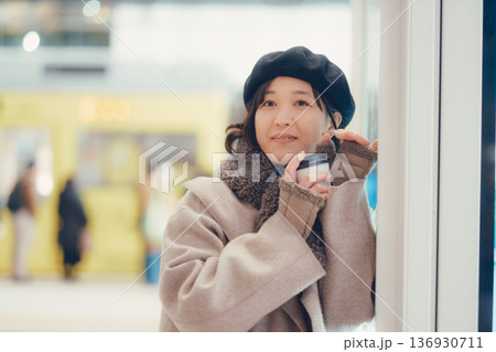 駅構内で歩きながらコーヒーを飲む30代女性 駅構内で歩きながらコーヒーを飲む30代女性 136930711