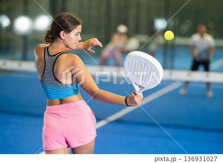 Padel game - girl with partners plays on tennis court 136931027