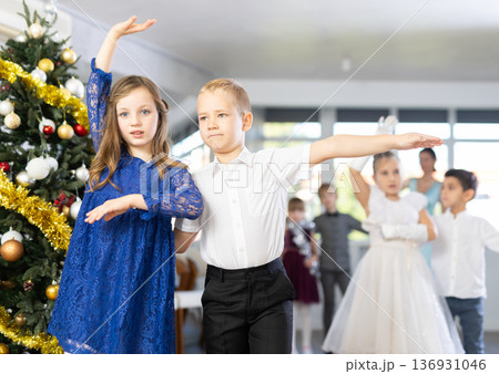 Christmas ball - beautifully dressed children dance the Viennese waltz near New Year tree Christmas ball - beautifully dressed children dance the Viennese waltz near New Year tree 136931046